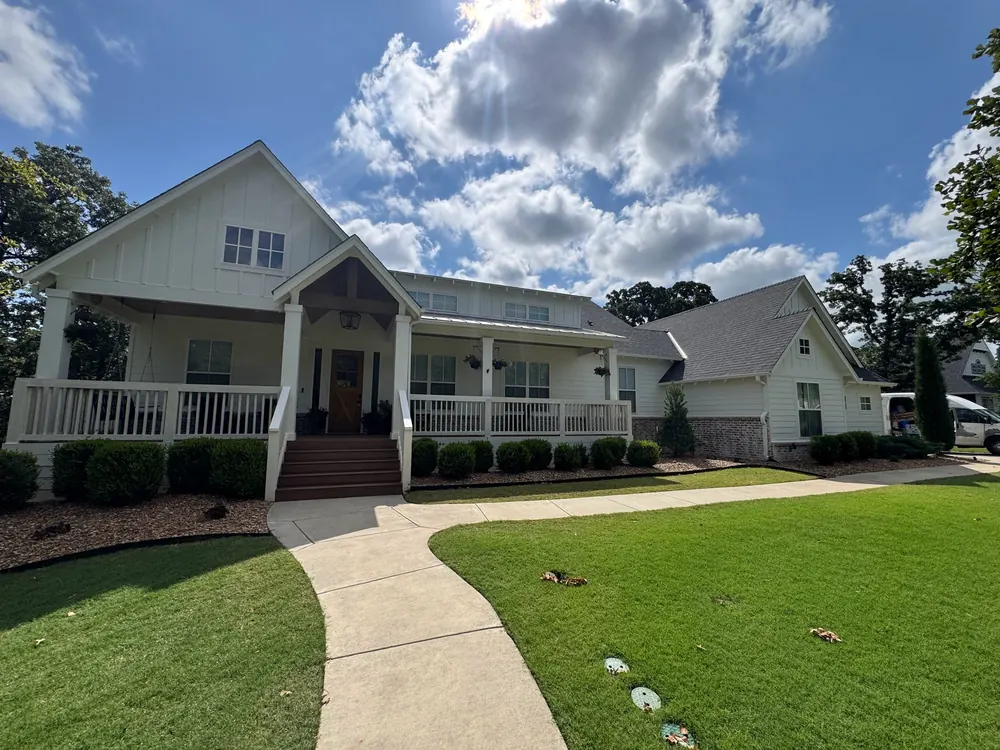 freshly painted white farmhouse exterior with dark trim and green lawn