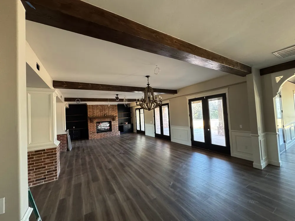 newly painted great room with warm neutral walls, white wainscoting and dark ceiling beams